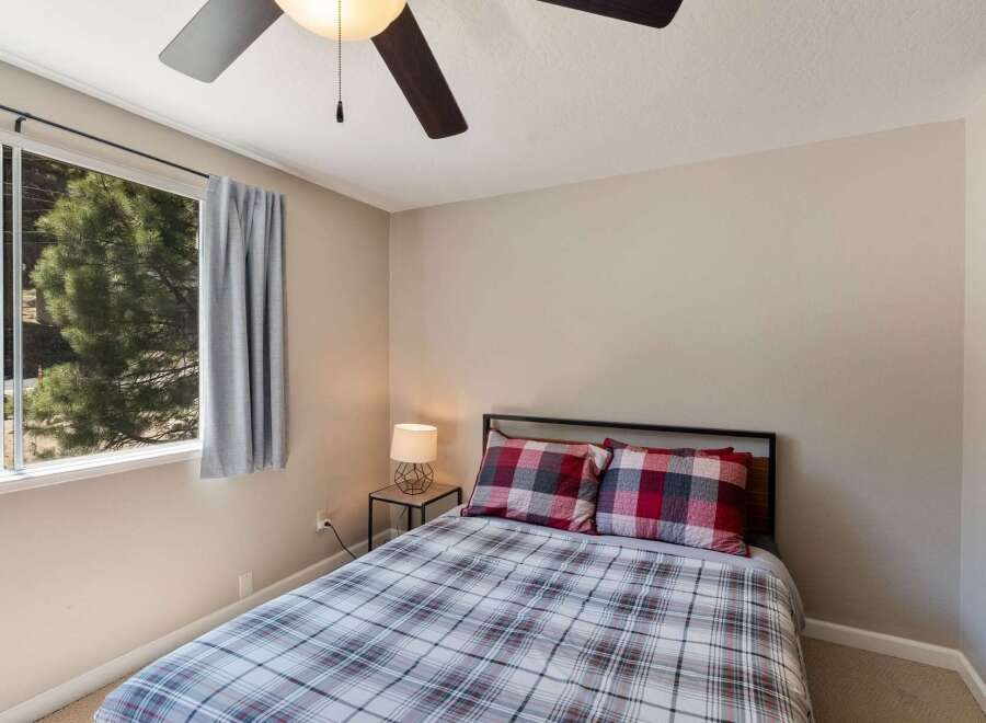 This cozy bedroom features a comfortable bed dressed in a charming plaid comforter and matching pillows.