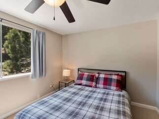 This cozy bedroom features a comfortable bed dressed in a charming plaid comforter and matching pillows.