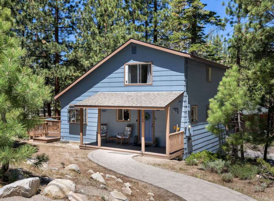 Nestled amidst tall pine trees, this charming blue home offers a serene mountain retreat.