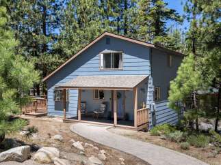 Nestled amidst tall pine trees, this charming blue home offers a serene mountain retreat.