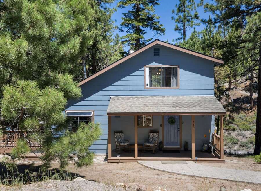 Charming blue home nestled among tall pine trees, offering a serene mountain retreat.
