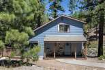 Charming blue home nestled among tall pine trees, offering a serene mountain retreat.