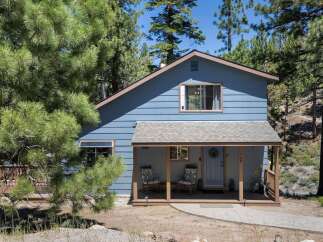 Charming blue home nestled among tall pine trees, offering a serene mountain retreat.