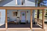 Welcome to this charming home featuring a welcoming covered porch with comfortable rocking chairs, perfect for enjoying the serene surroundings.