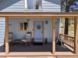 Welcome to this charming home featuring a welcoming covered porch with comfortable rocking chairs, perfect for enjoying the serene surroundings.