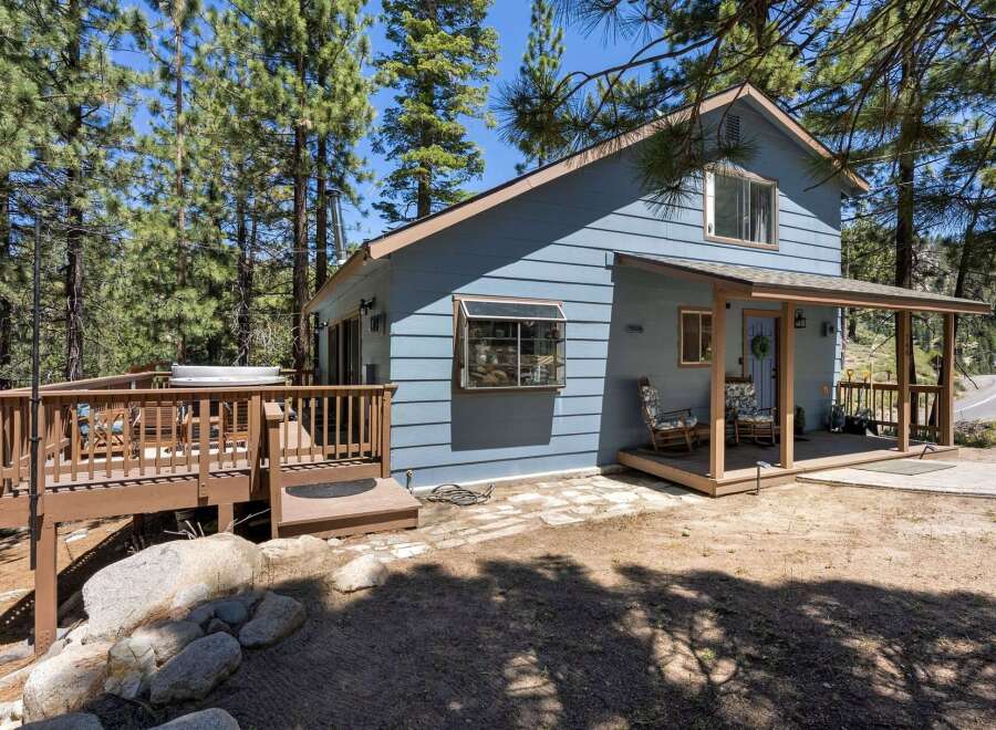 Escape to this charming blue cabin nestled among tall pine trees, offering a serene mountain retreat.