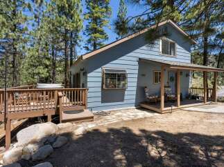 Escape to this charming blue cabin nestled among tall pine trees, offering a serene mountain retreat.