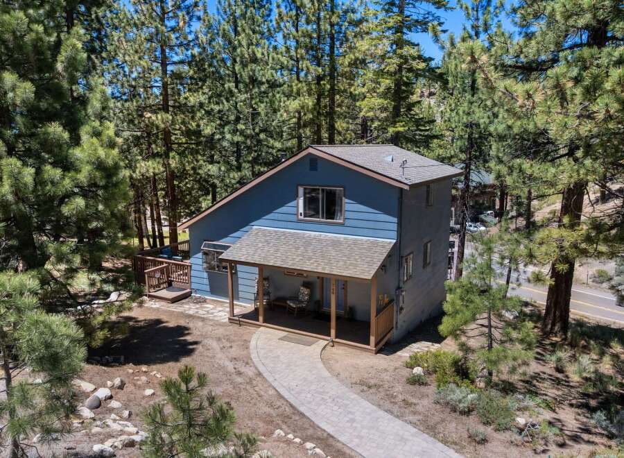 Nestled amidst tall pine trees, this charming blue home offers a serene mountain retreat.