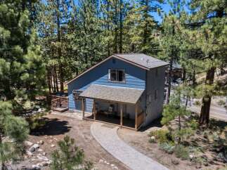 Nestled amidst tall pine trees, this charming blue home offers a serene mountain retreat.