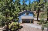 Nestled amidst tall pine trees, this charming blue home offers a serene mountain retreat.