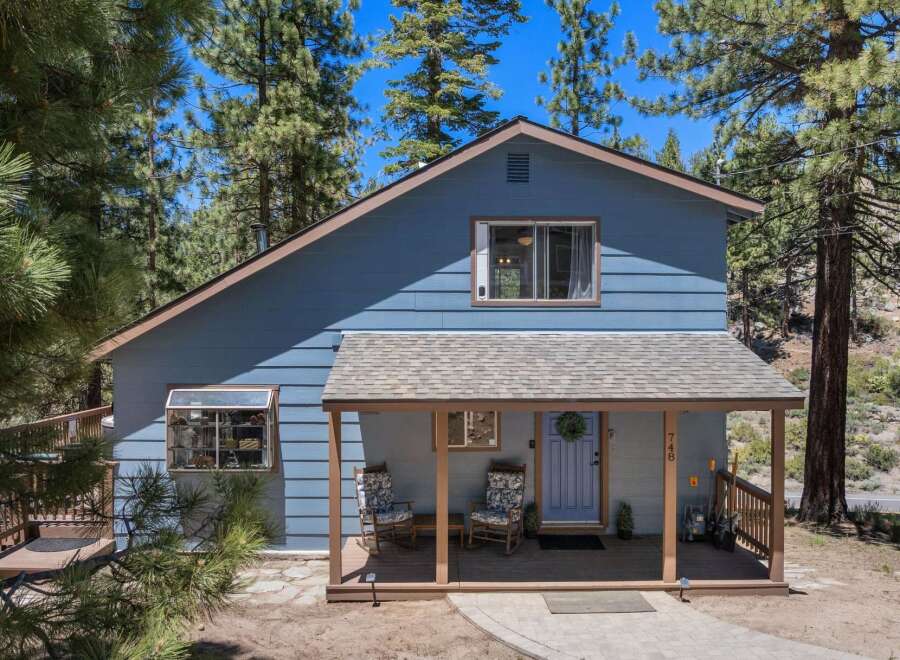 Nestled among tall pine trees, this charming blue home offers a serene mountain retreat.
