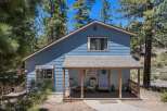 Nestled among tall pine trees, this charming blue home offers a serene mountain retreat.