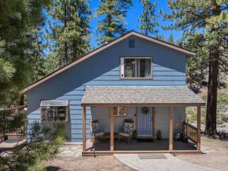 Nestled among tall pine trees, this charming blue home offers a serene mountain retreat.