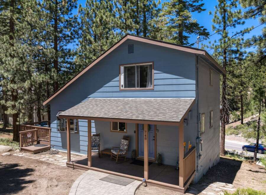Discover this charming blue home nestled among tall pine trees, offering a serene mountain retreat.
