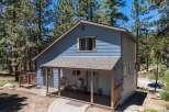 Discover this charming blue home nestled among tall pine trees, offering a serene mountain retreat.