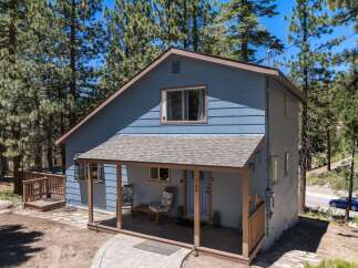 Discover this charming blue home nestled among tall pine trees, offering a serene mountain retreat.