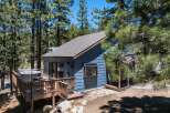 Escape to this charming blue cabin nestled among tall pine trees, offering a serene mountain retreat.