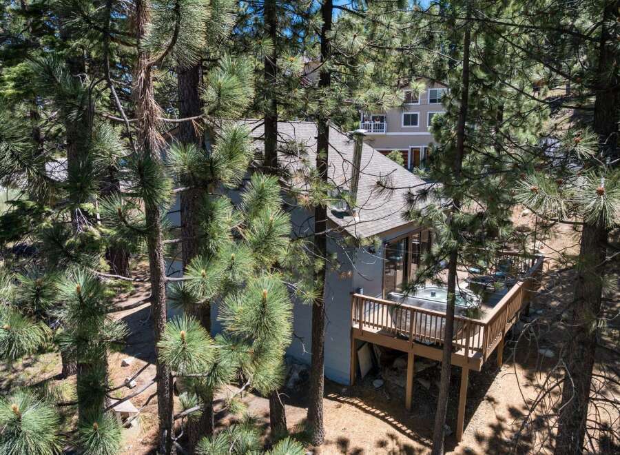 Nestled among tall pine trees, this charming home offers a private oasis with a spacious wooden deck featuring a relaxing hot tub.