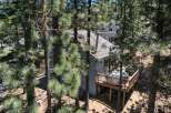 Nestled among tall pine trees, this charming home offers a private oasis with a spacious wooden deck featuring a relaxing hot tub.