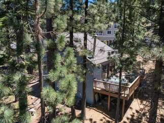 Nestled among tall pine trees, this charming home offers a private oasis with a spacious wooden deck featuring a relaxing hot tub.