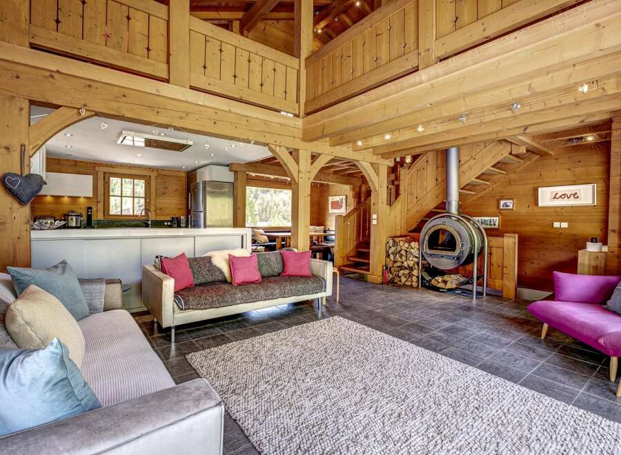 Experience rustic charm in this stunning wooden cabin living space, featuring a cozy fireplace and an open-plan kitchen.