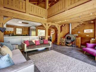 Experience rustic charm in this stunning wooden cabin living space, featuring a cozy fireplace and an open-plan kitchen.