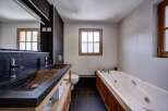 Experience luxury in this modern bathroom featuring a sleek double vanity with stone sinks and chrome fixtures.