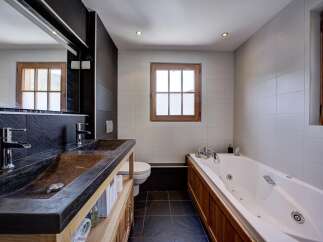 Experience luxury in this modern bathroom featuring a sleek double vanity with stone sinks and chrome fixtures.