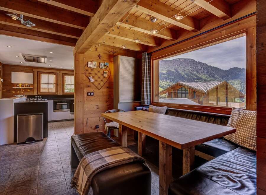 Experience breathtaking mountain views from this charming dining area, featuring a rustic wooden table and comfortable leather banquette seating.