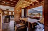 Experience breathtaking mountain views from this charming dining area, featuring a rustic wooden table and comfortable leather banquette seating.