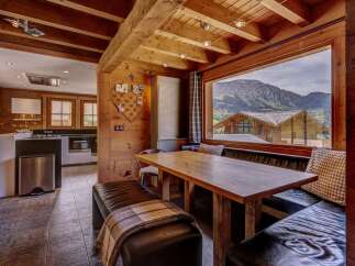 Experience breathtaking mountain views from this charming dining area, featuring a rustic wooden table and comfortable leather banquette seating.