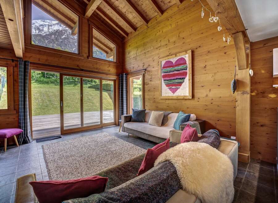 Experience the ultimate mountain retreat in this stunning chalet living room, featuring a vaulted wooden ceiling and expansive windows that frame breathtaking alpine views.