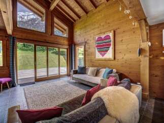 Experience the ultimate mountain retreat in this stunning chalet living room, featuring a vaulted wooden ceiling and expansive windows that frame breathtaking alpine views.
