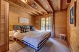 Experience rustic charm in this cozy bedroom, featuring warm wood paneling throughout and exposed ceiling beams.