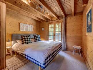 Experience rustic charm in this cozy bedroom, featuring warm wood paneling throughout and exposed ceiling beams.