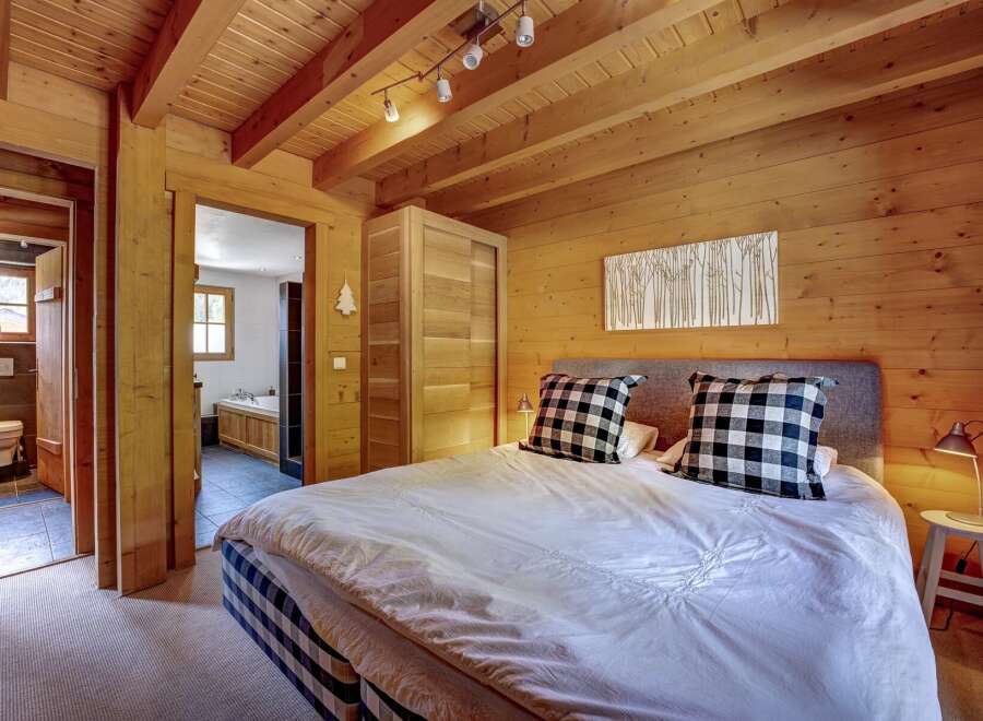 Experience rustic charm in this cozy bedroom featuring a king-sized bed with plush checkered pillows and a white duvet.
