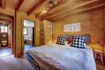 Experience rustic charm in this cozy bedroom featuring a king-sized bed with plush checkered pillows and a white duvet.