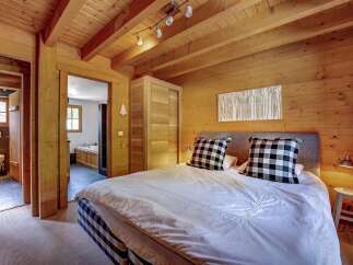 Experience rustic charm in this cozy bedroom featuring a king-sized bed with plush checkered pillows and a white duvet.