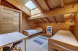 Experience cozy mountain living in this charming attic bedroom, featuring two comfortable twin beds and a dedicated workspace.