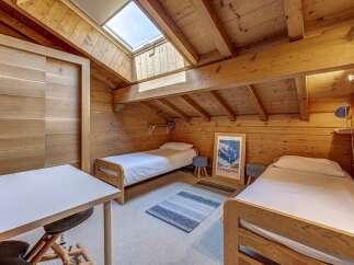 Experience cozy mountain living in this charming attic bedroom, featuring two comfortable twin beds and a dedicated workspace.