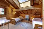 Experience cozy living in this charming attic bedroom, featuring warm wooden walls and a vaulted ceiling with a skylight that floods the space with natural light.