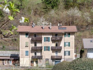 Discover this charming multi-story building nestled against a lush, tree-covered hillside, offering a serene living environment.
