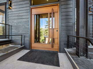 Step into luxury with this stunning modern entryway, featuring a striking natural wood door with a large glass panel that floods the space with natural light.