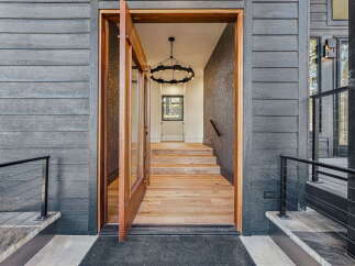 Step into luxury with this stunning entryway featuring a grand wooden door that opens to reveal a beautifully lit foyer.