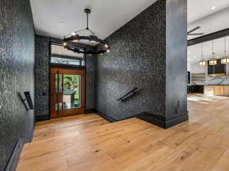 Step into a grand entryway featuring striking dark floral wallpaper and warm hardwood floors.