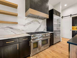 Experience luxury in this modern kitchen, featuring sleek dark cabinetry complemented by a stunning marble backsplash and a professional-grade stainless steel range.