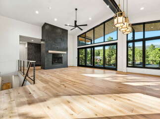 Experience modern luxury in this stunning living room featuring a dramatic floor-to-ceiling fireplace and expansive windows that flood the space with natural light.