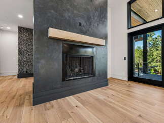 Experience modern living with this stunning fireplace featuring a natural wood mantel and a dark, textured surround.