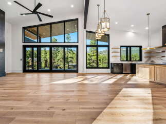 Experience modern luxury in this stunning open-concept living space, featuring soaring vaulted ceilings and expansive windows that flood the room with natural light.