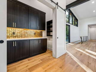 Experience modern luxury with this stunning kitchen featuring dark wood cabinetry and a dazzling gold tile backsplash.